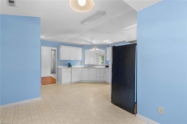 kitchen featuring black refrigerator, white cabinetry, sink, and dishwasher