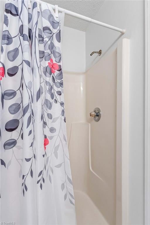 bathroom featuring curtained shower and a textured ceiling