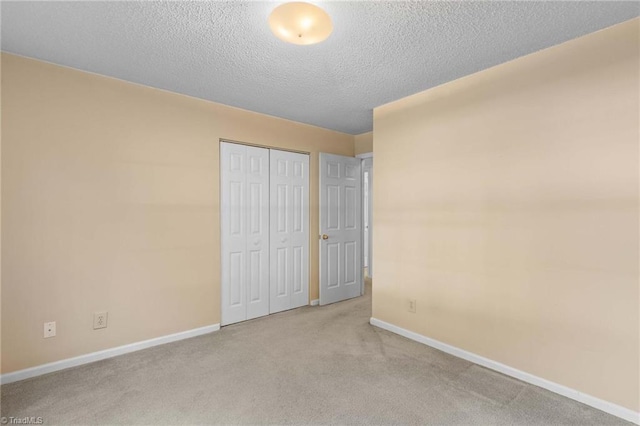 unfurnished bedroom with a closet, a textured ceiling, and light carpet