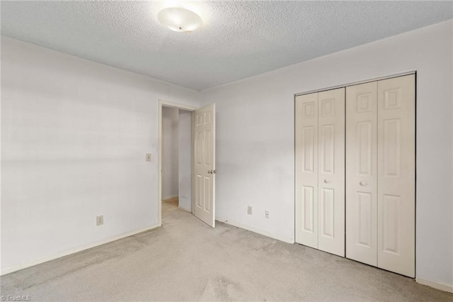 unfurnished bedroom featuring a closet, a textured ceiling, and light colored carpet