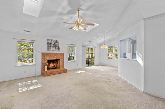 unfurnished living room with vaulted ceiling with skylight, carpet, ceiling fan, and plenty of natural light