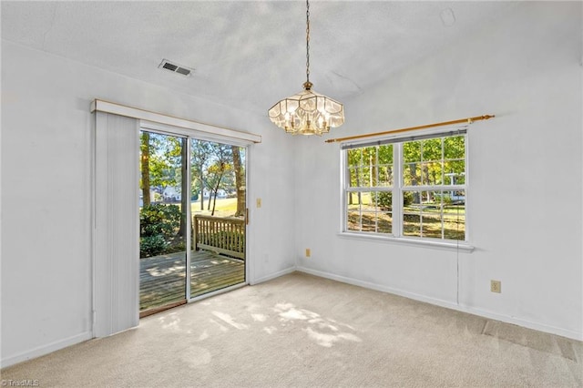 spare room featuring a textured ceiling, vaulted ceiling, a notable chandelier, and carpet floors