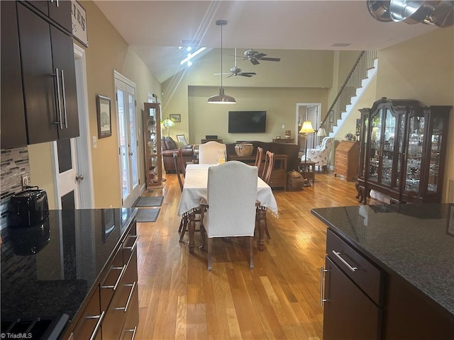 dining area with light wood-style floors, a ceiling fan, and stairs