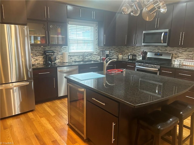 kitchen featuring wine cooler, a breakfast bar area, stainless steel appliances, light wood-style floors, and a sink