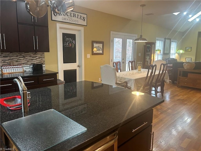 kitchen featuring decorative backsplash, open floor plan, wood finished floors, french doors, and pendant lighting