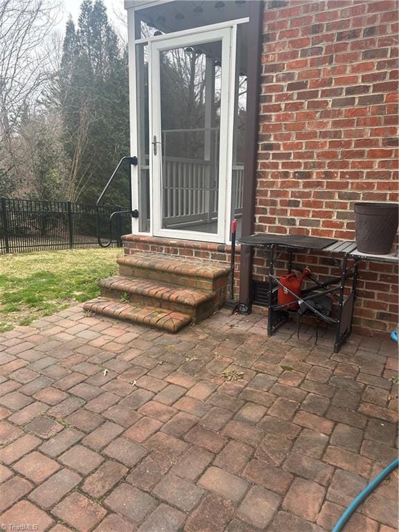 entrance to property with brick siding, a patio area, and fence