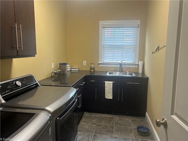 clothes washing area featuring baseboards, cabinet space, a sink, and washing machine and clothes dryer