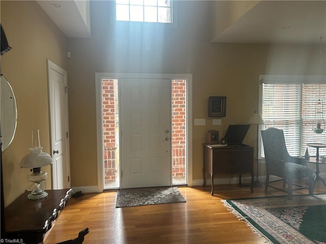 entryway featuring a high ceiling, baseboards, and wood finished floors