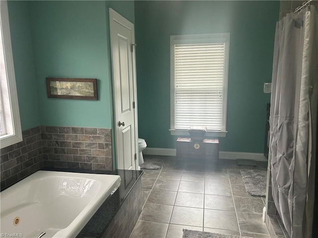 bathroom with toilet, a garden tub, baseboards, and tile patterned floors