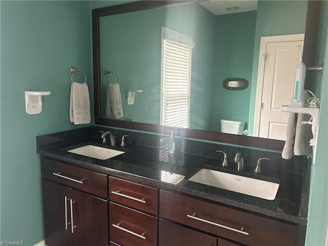 full bath with double vanity, a sink, and toilet