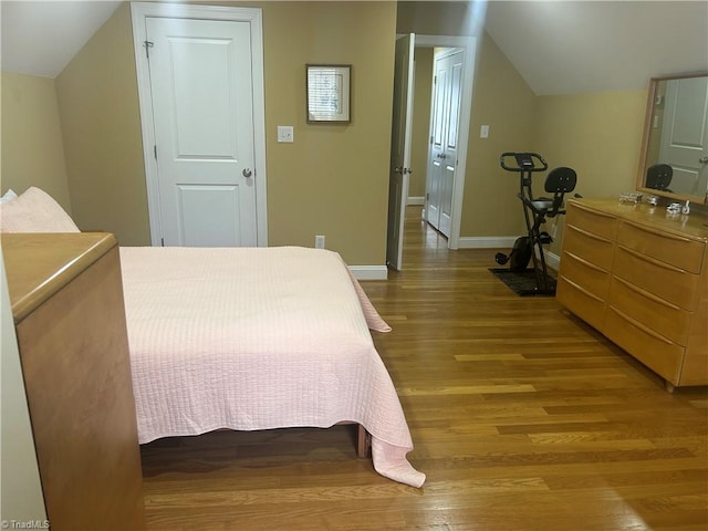 bedroom featuring light wood-style floors, baseboards, and vaulted ceiling