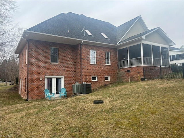 rear view of house with a sunroom, a yard, cooling unit, french doors, and brick siding