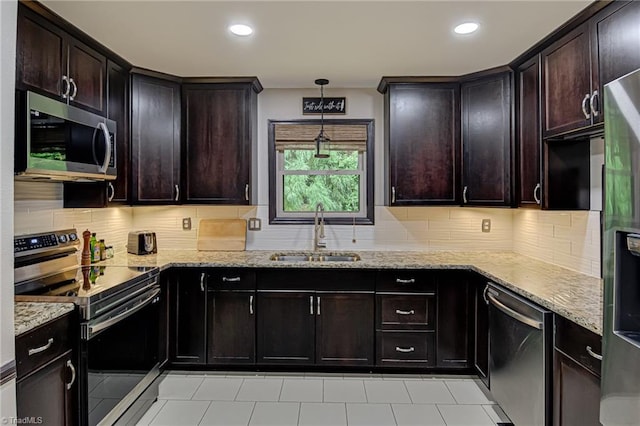 kitchen with backsplash, light stone counters, appliances with stainless steel finishes, and a sink