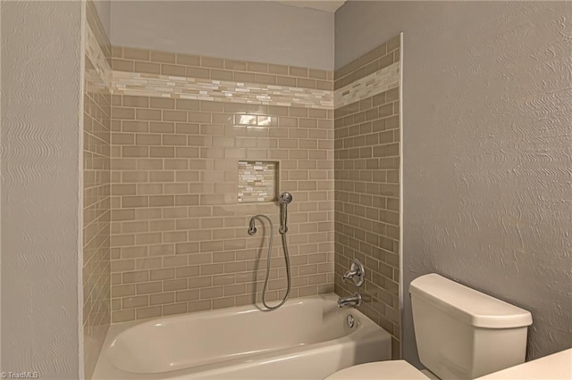 bathroom with a textured wall, toilet, and shower / tub combination