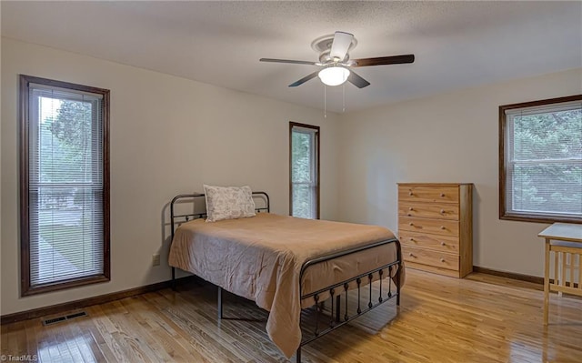 bedroom featuring visible vents, baseboards, light wood-style floors, and a ceiling fan