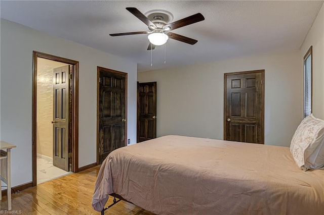 bedroom with a ceiling fan, light wood-style floors, baseboards, and connected bathroom