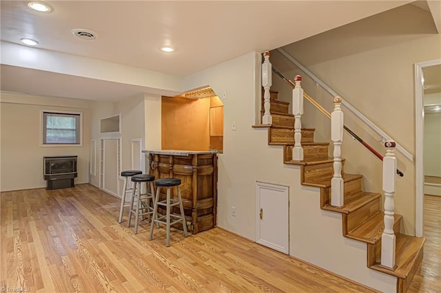 bar featuring stairs, visible vents, wood finished floors, and a dry bar