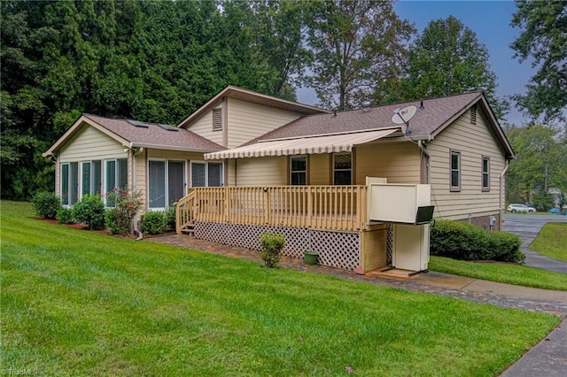 ranch-style house with a deck, a front yard, and a shingled roof