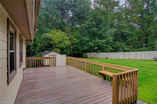 deck with a yard, an outdoor structure, a fenced backyard, and a shed