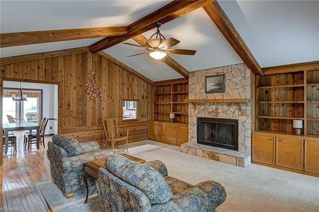 living area featuring built in features, wood walls, lofted ceiling with beams, a fireplace, and wood-type flooring