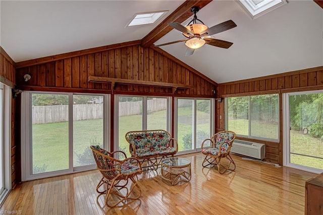 sunroom / solarium with vaulted ceiling with skylight, a wall mounted AC, and ceiling fan