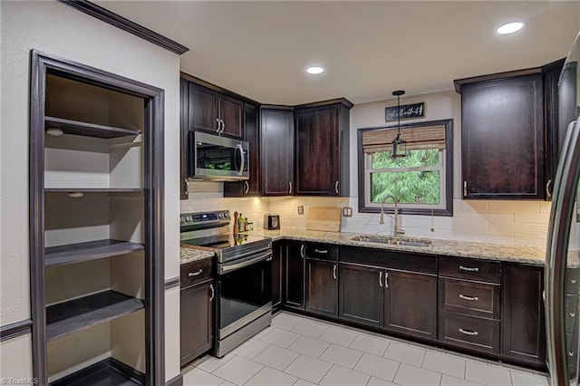 kitchen with tasteful backsplash, light stone countertops, dark brown cabinetry, stainless steel appliances, and a sink