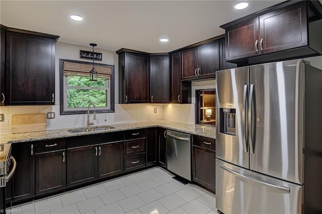 kitchen with light stone countertops, tasteful backsplash, appliances with stainless steel finishes, and a sink