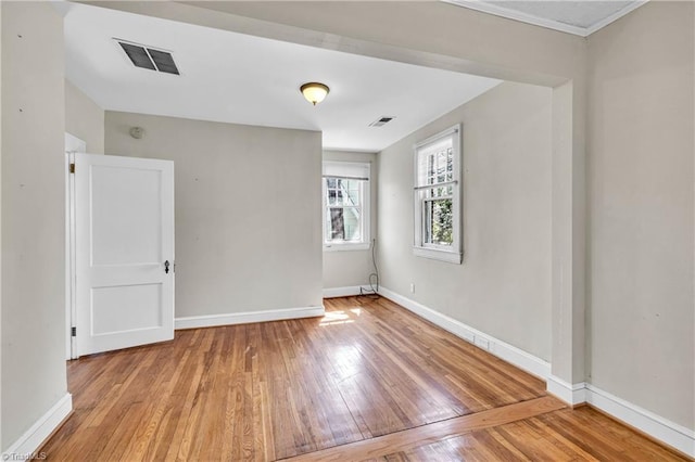 unfurnished room featuring hardwood / wood-style floors, baseboards, and visible vents