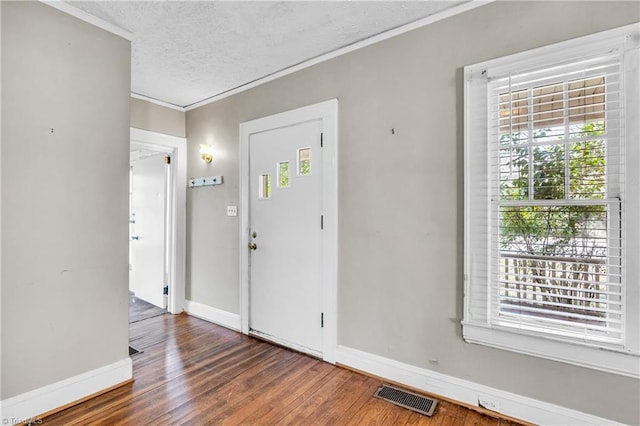 foyer featuring baseboards, wood finished floors, visible vents, and a textured ceiling