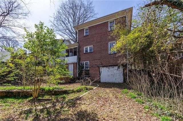 back of house featuring brick siding and an attached garage