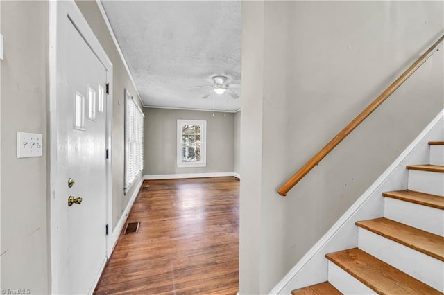 foyer entrance featuring wood finished floors, visible vents, ceiling fan, stairs, and a textured ceiling