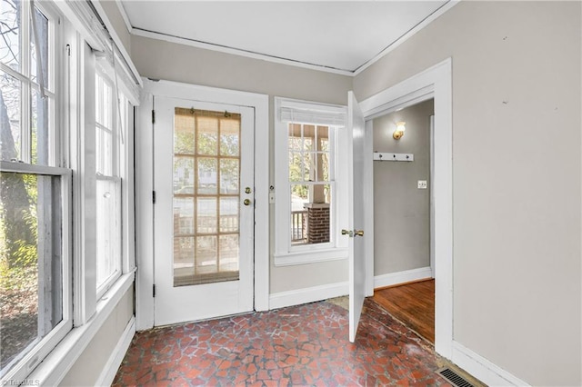 doorway with visible vents, crown molding, and baseboards