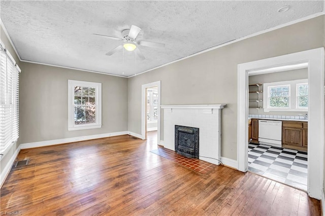 unfurnished living room featuring a brick fireplace, plenty of natural light, visible vents, and ornamental molding