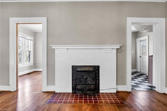 room details with baseboards, a brick fireplace, and wood finished floors