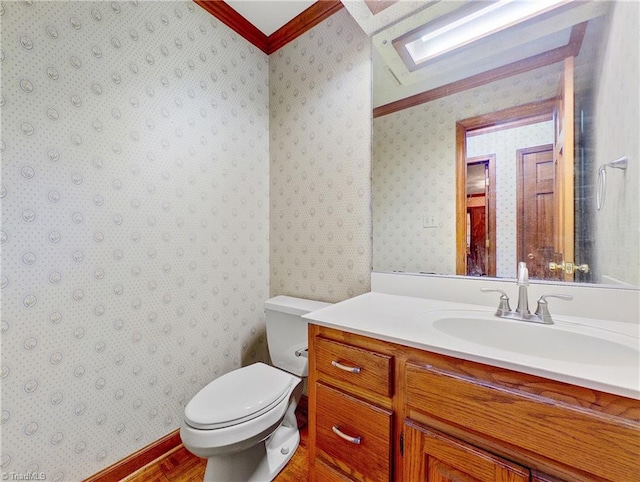 bathroom featuring toilet, vanity, a skylight, and crown molding