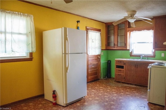 2446 Greenway St, Burlington, NC 27217 - kitchen featuring white appliances, ceiling fan, brown cabinets, glass insert cabinets, and ornamental molding