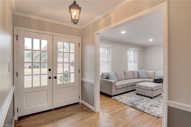 doorway to outside featuring french doors, ornamental molding, and light wood-type flooring