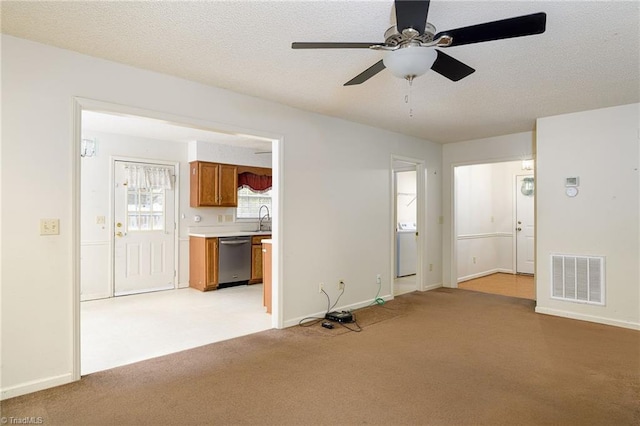 unfurnished living room featuring ceiling fan, sink, a textured ceiling, and light carpet