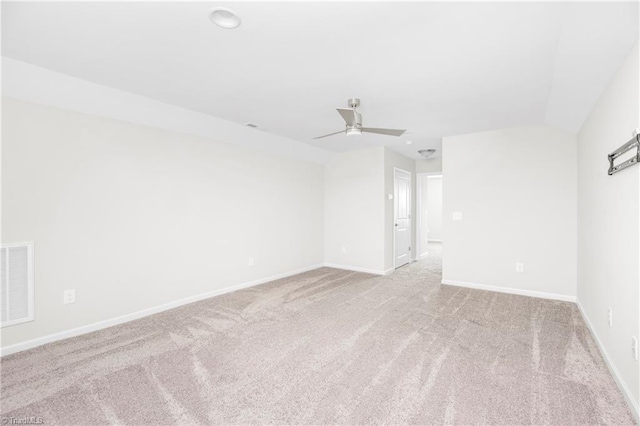 spare room with light carpet, vaulted ceiling, and ceiling fan