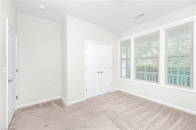 unfurnished bedroom with light carpet, multiple windows, and a closet