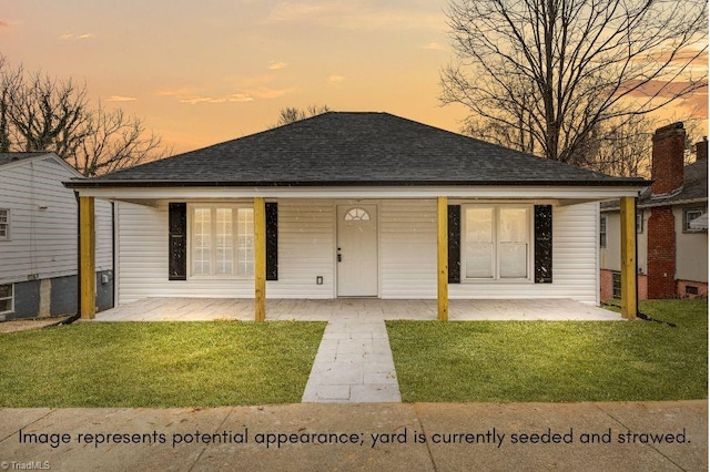 back house at dusk featuring a yard and a porch