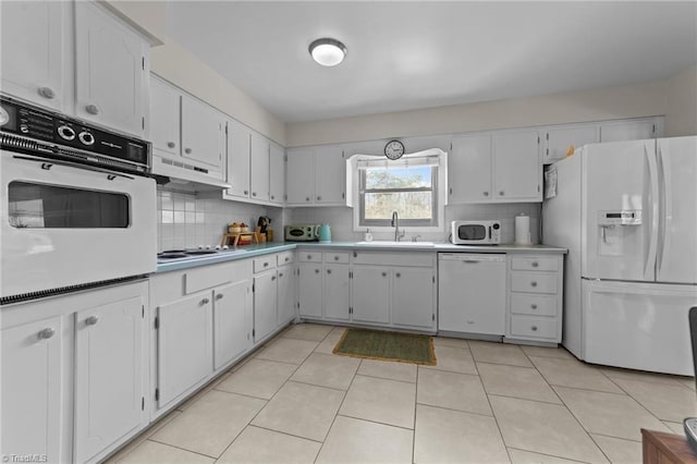 kitchen with white appliances, a sink, light countertops, under cabinet range hood, and backsplash