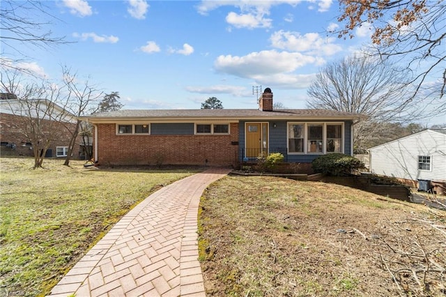 ranch-style home with a chimney, a front lawn, and brick siding