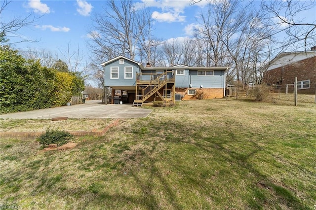 rear view of property with fence, stairs, a yard, concrete driveway, and a carport