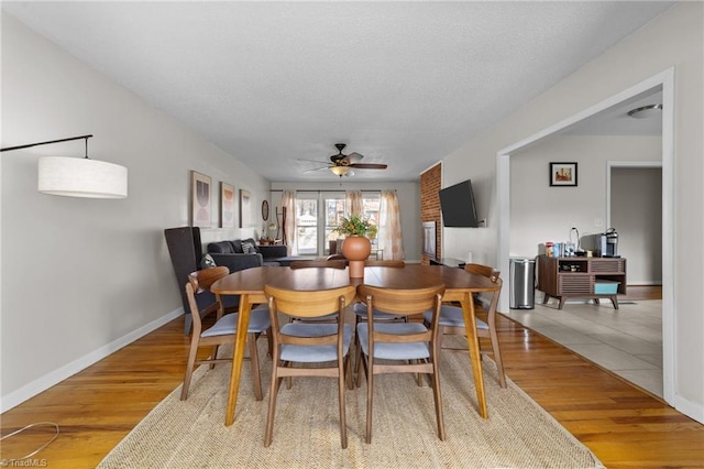 dining space featuring light wood-style floors, ceiling fan, baseboards, and a textured ceiling