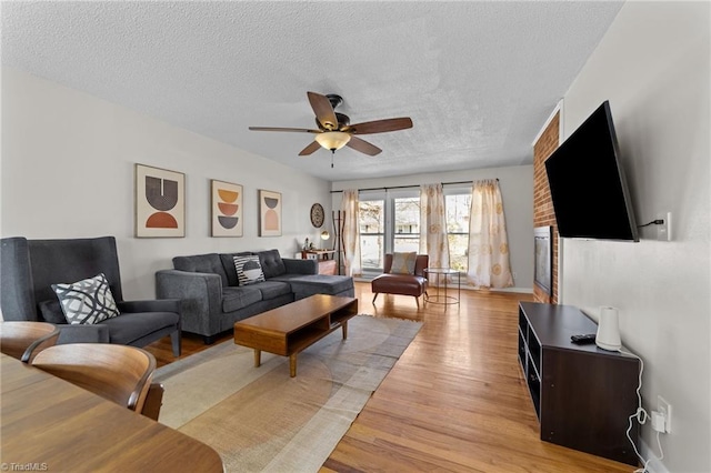 living room with light wood finished floors, ceiling fan, and a textured ceiling