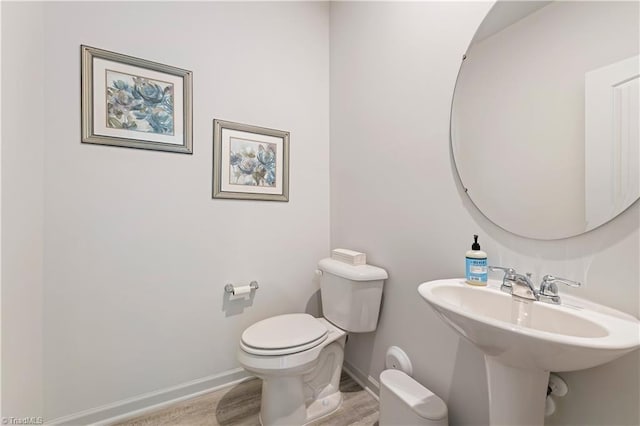 bathroom featuring toilet, baseboards, a sink, and wood finished floors