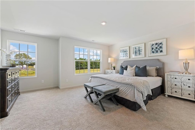 bedroom featuring baseboards, multiple windows, visible vents, and light colored carpet