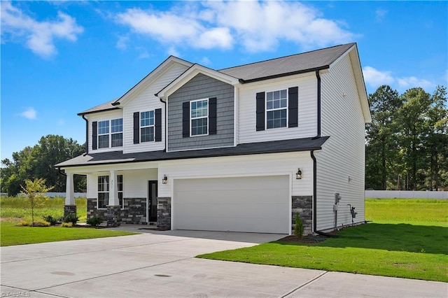 view of front facade with stone siding, a front yard, an attached garage, driveway, and a porch