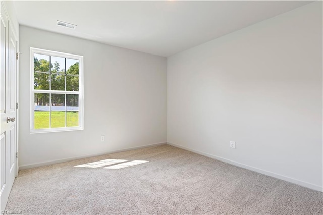 carpeted spare room with baseboards, visible vents, and plenty of natural light